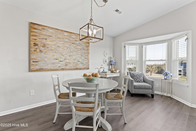 dining area featuring baseboards, visible vents, dark wood finished floors, lofted ceiling, and an inviting chandelier