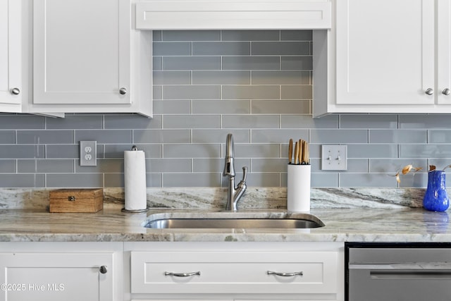 room details with white cabinets, dishwasher, a sink, light stone countertops, and backsplash