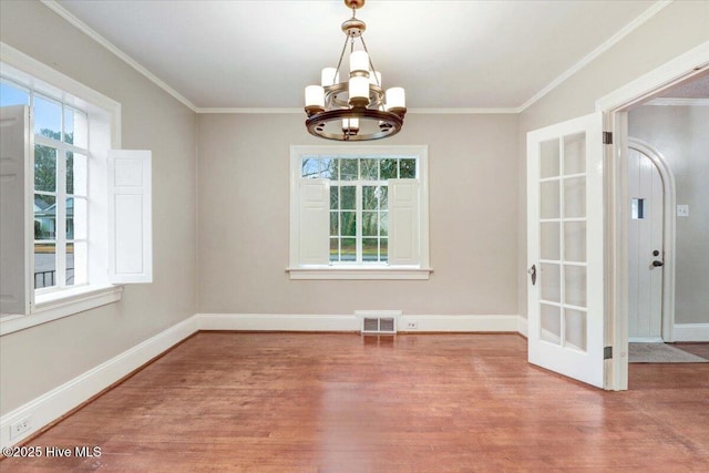 unfurnished dining area with an inviting chandelier, hardwood / wood-style flooring, and ornamental molding