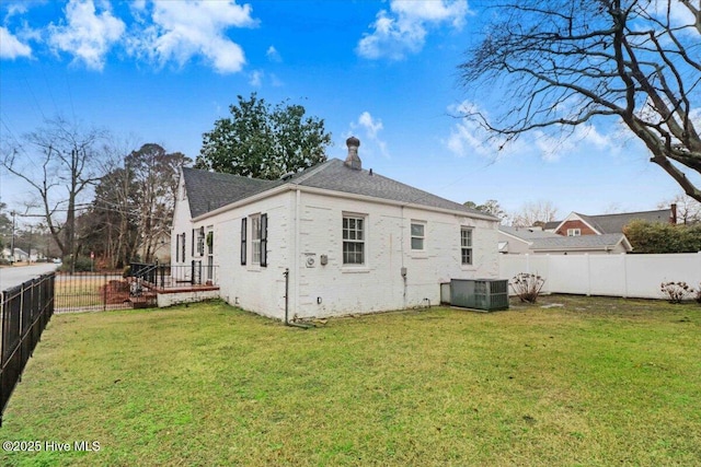 rear view of property with cooling unit and a lawn