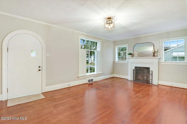 unfurnished living room featuring hardwood / wood-style flooring, ornamental molding, and a textured ceiling