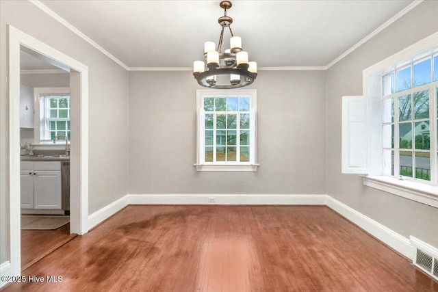 unfurnished dining area featuring an inviting chandelier, ornamental molding, and hardwood / wood-style flooring