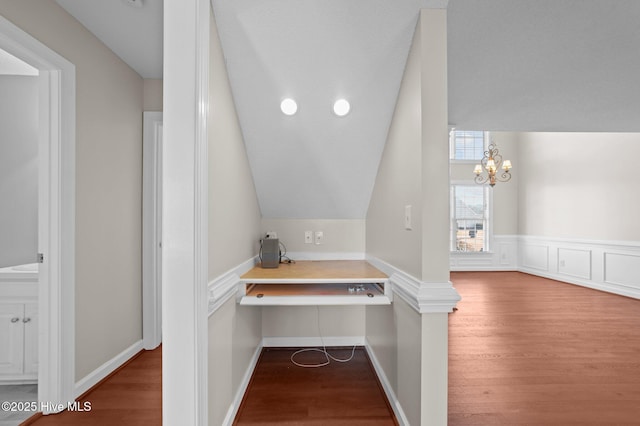 hallway featuring an inviting chandelier, lofted ceiling, and hardwood / wood-style floors