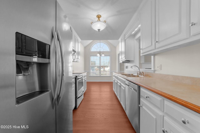 kitchen with sink, vaulted ceiling, appliances with stainless steel finishes, light hardwood / wood-style floors, and white cabinets