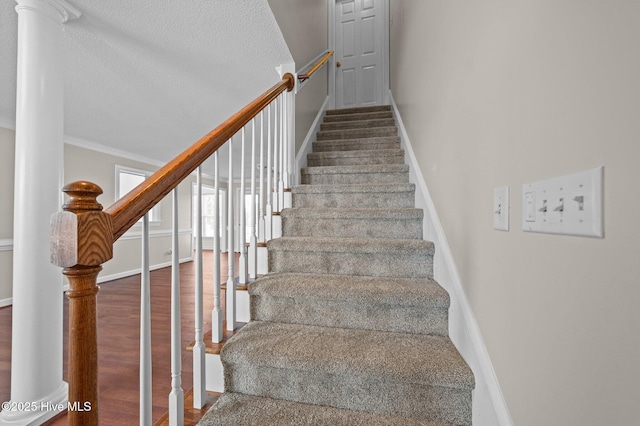 stairway featuring hardwood / wood-style flooring, ornamental molding, and a textured ceiling