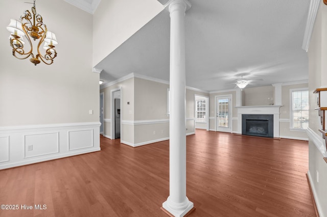 unfurnished living room with hardwood / wood-style floors, ceiling fan with notable chandelier, ornamental molding, and decorative columns