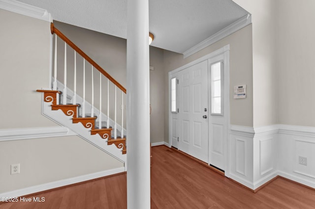 entrance foyer with wood-type flooring, ornamental molding, and a textured ceiling