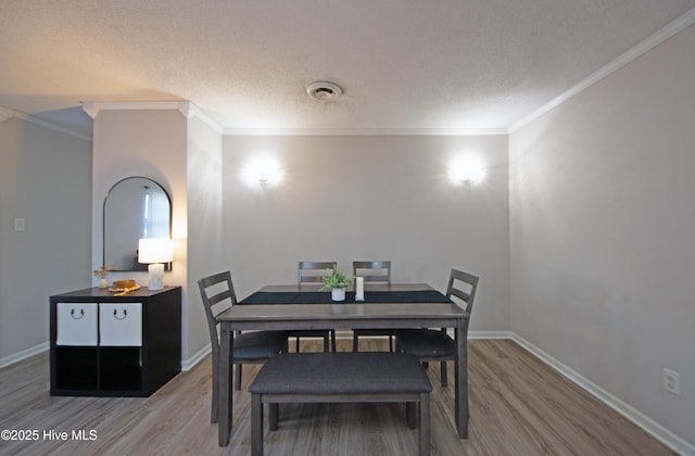 dining space with hardwood / wood-style flooring, ornamental molding, and a textured ceiling