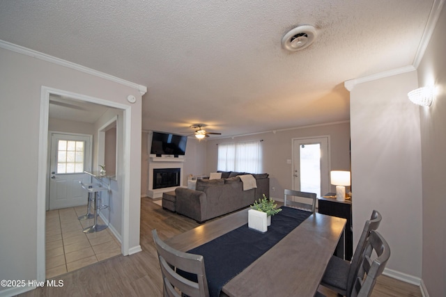 dining space with wood-type flooring, ceiling fan, a textured ceiling, and crown molding