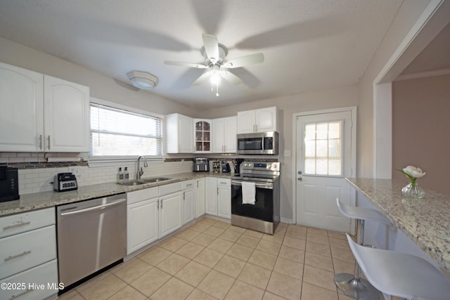 kitchen featuring white cabinetry, appliances with stainless steel finishes, light stone countertops, and sink