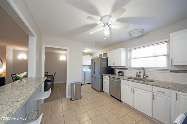 kitchen with stainless steel appliances, sink, white cabinets, and independent washer and dryer