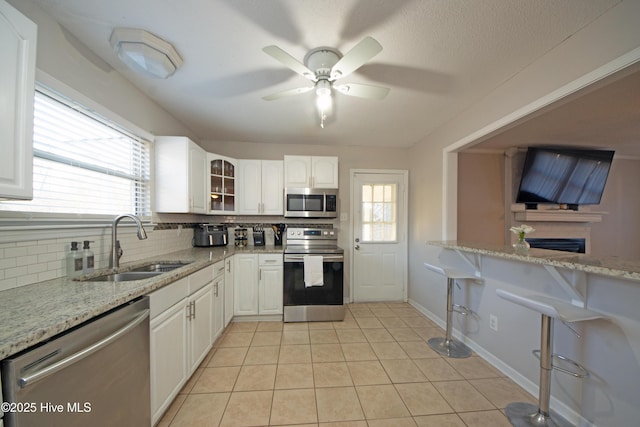 kitchen featuring stainless steel appliances, white cabinets, and light stone counters