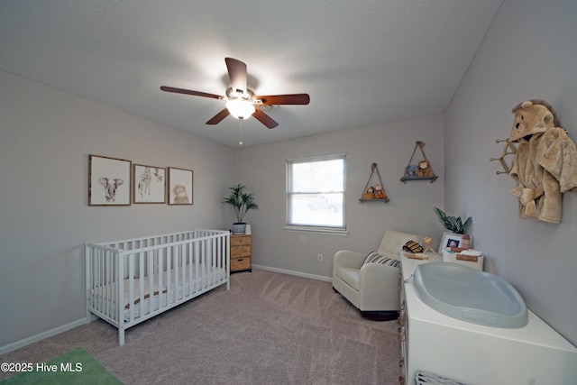 carpeted bedroom featuring ceiling fan, a textured ceiling, and a crib