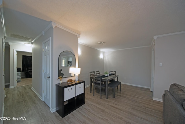 dining area with crown molding, wood-type flooring, and a textured ceiling