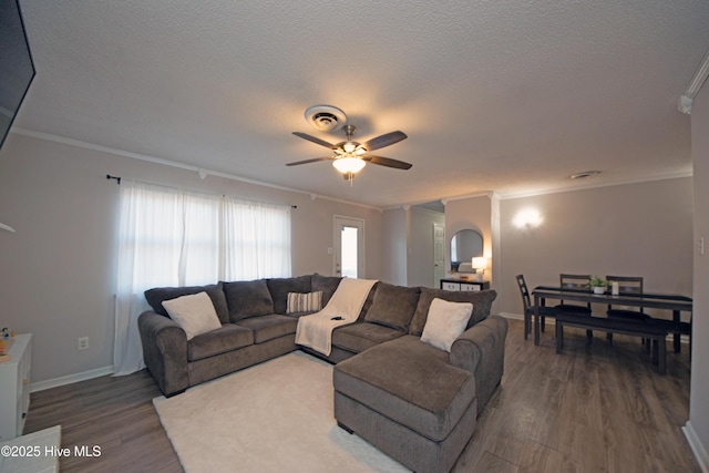 living room featuring wood-type flooring, ornamental molding, ceiling fan, and a textured ceiling