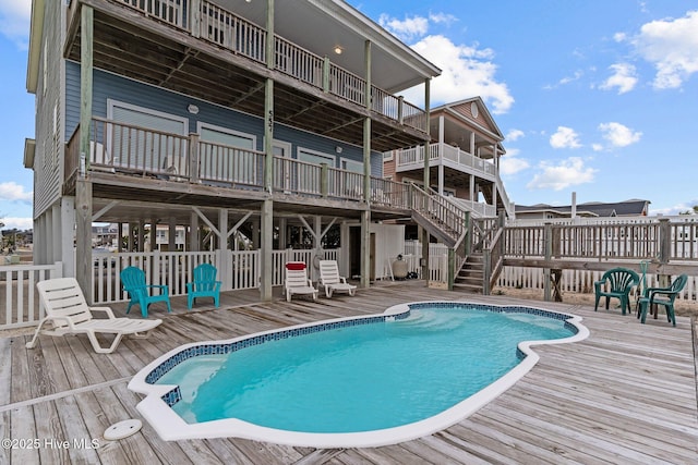 view of swimming pool with a fenced in pool, a wooden deck, and stairway