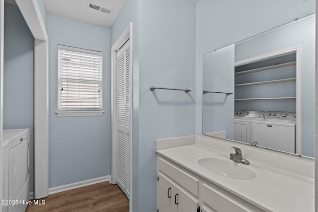 bathroom with a closet, separate washer and dryer, wood finished floors, and visible vents