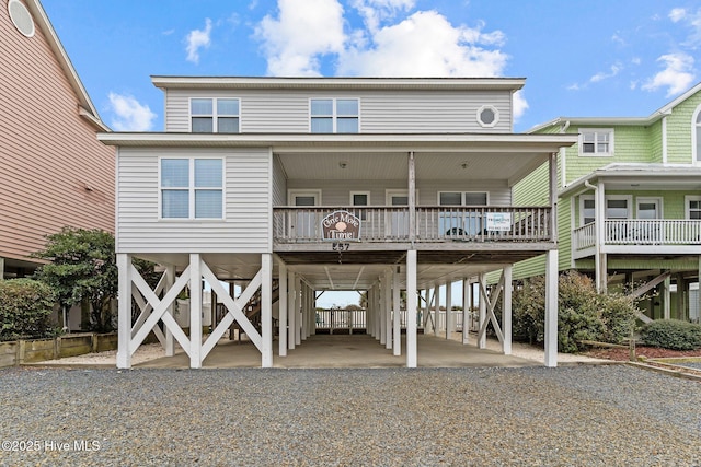 rear view of property featuring a carport, gravel driveway, and stairs