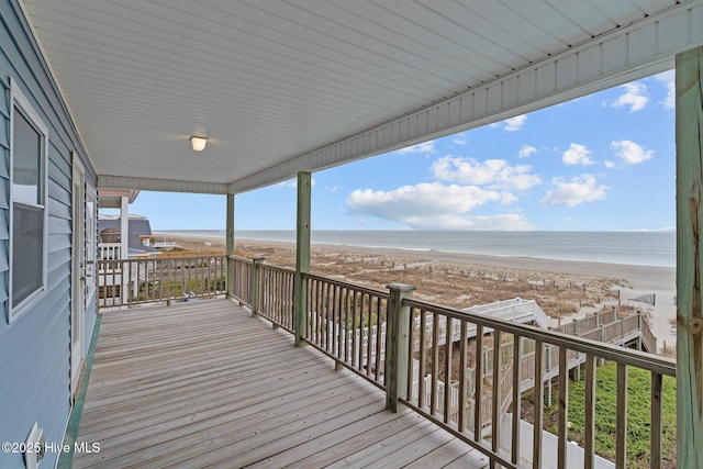 wooden terrace featuring a beach view and a water view