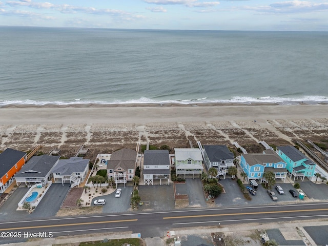 drone / aerial view featuring a water view, a view of the beach, and a residential view