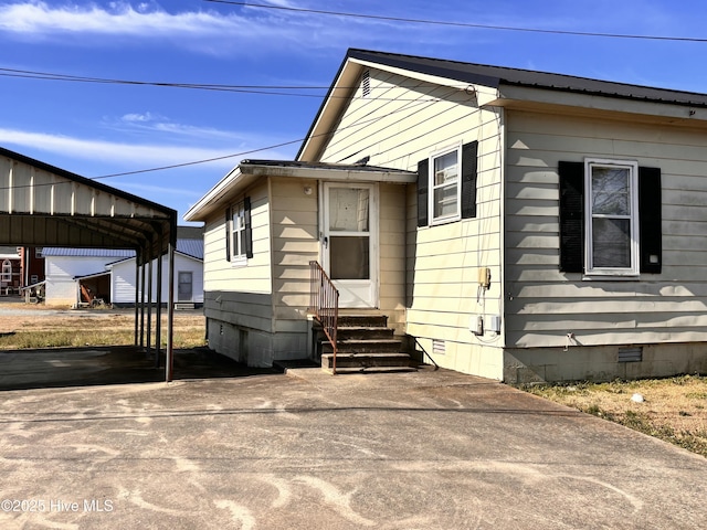 view of front of home with a carport, entry steps, crawl space, and driveway