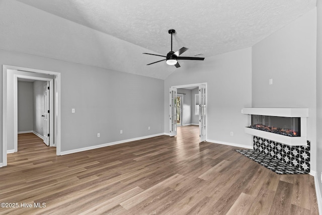 6148 Sugar Pine Dr, Wilmington, NC 28412 - unfurnished living room featuring a tile fireplace, ceiling fan, lofted ceiling, a textured ceiling, and wood finished floors