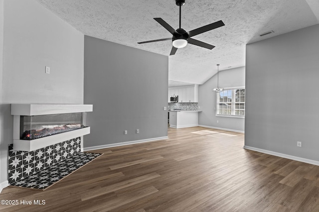 6148 Sugar Pine Dr, Wilmington, NC 28412 - unfurnished living room featuring a textured ceiling, a ceiling fan, vaulted ceiling, wood finished floors, and a tile fireplace