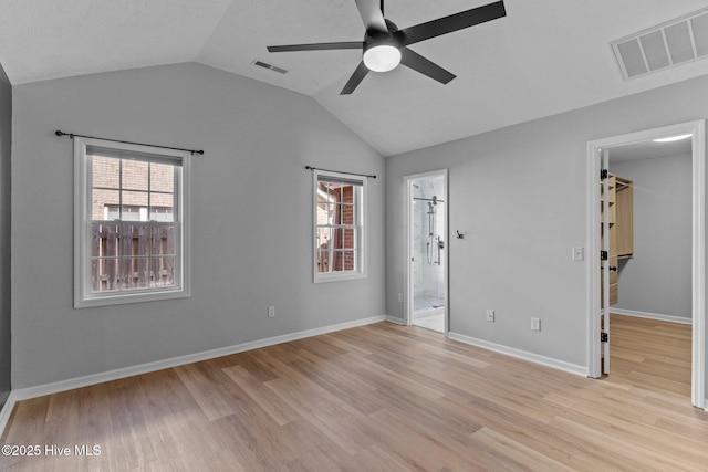 6148 Sugar Pine Dr, Wilmington, NC 28412 - unfurnished bedroom with a walk in closet, light wood-type flooring, vaulted ceiling, connected bathroom, and ceiling fan