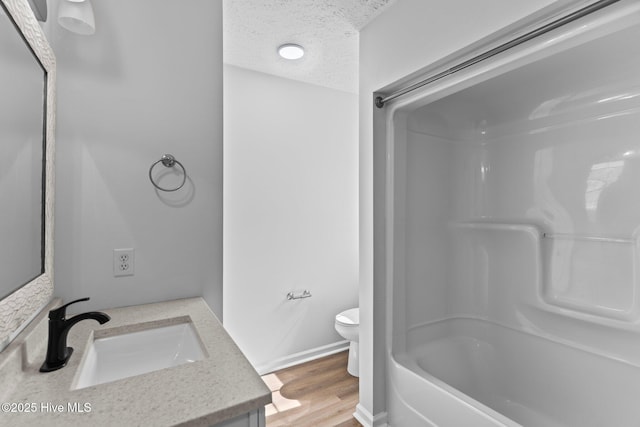 full bathroom featuring shower / washtub combination, toilet, a textured ceiling, vanity, and hardwood / wood-style floors