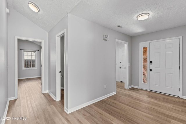 entrance foyer with light hardwood / wood-style flooring, a textured ceiling, and lofted ceiling