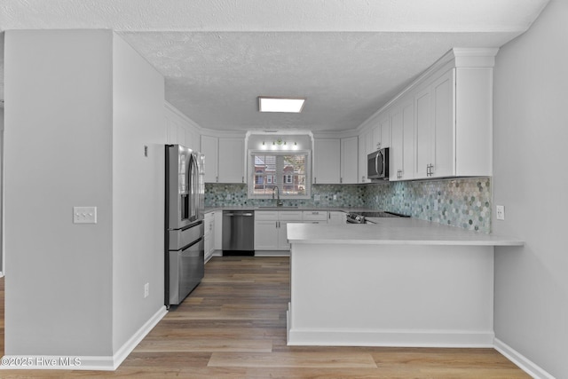 6148 Sugar Pine Dr, Wilmington, NC 28412 - kitchen with stainless steel appliances, a sink, a peninsula, tasteful backsplash, and light countertops