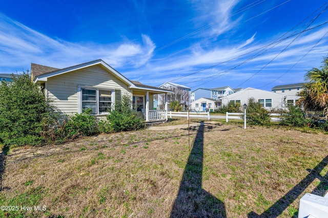 exterior space featuring fence, a front lawn, and covered porch