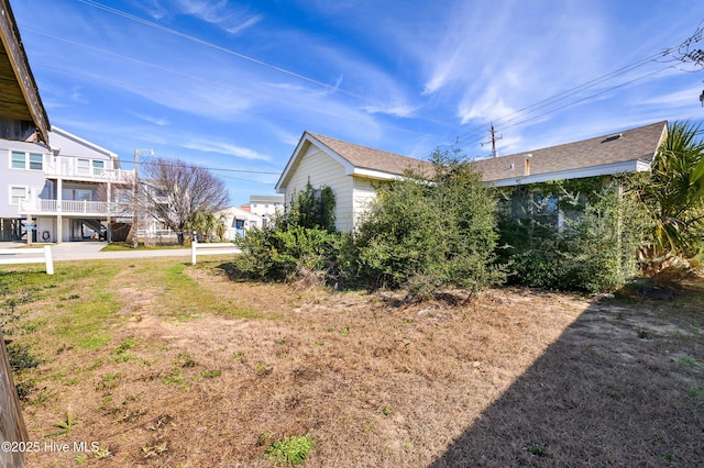 view of side of property featuring roof with shingles and a lawn