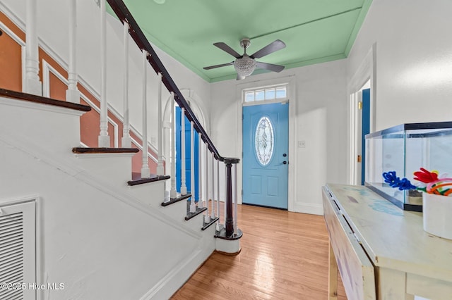 foyer entrance with light wood finished floors, baseboards, ornamental molding, and a ceiling fan