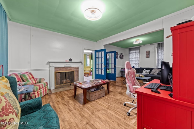 home office featuring a high end fireplace, french doors, and light wood finished floors