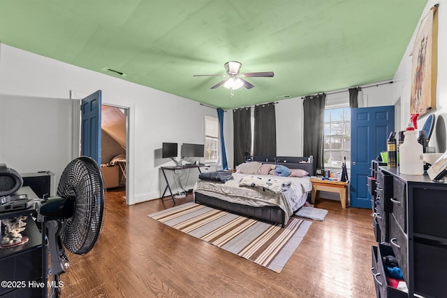 bedroom with ceiling fan, multiple windows, visible vents, and wood finished floors