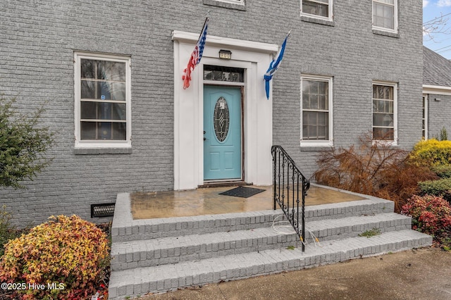 view of exterior entry featuring crawl space and brick siding