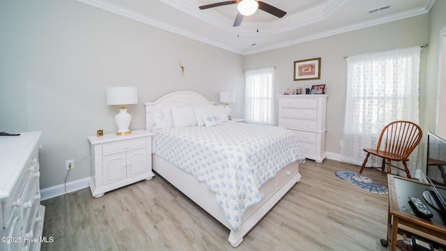 bedroom featuring ceiling fan, ornamental molding, a raised ceiling, and light hardwood / wood-style flooring