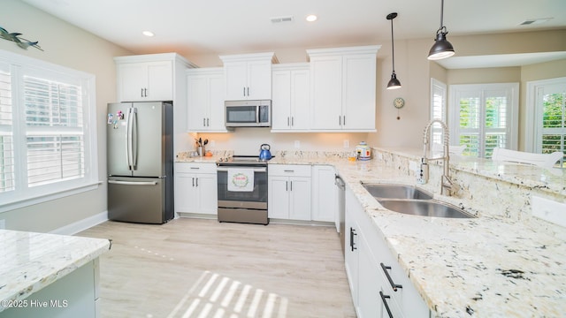 kitchen with sink, decorative light fixtures, white cabinets, and appliances with stainless steel finishes