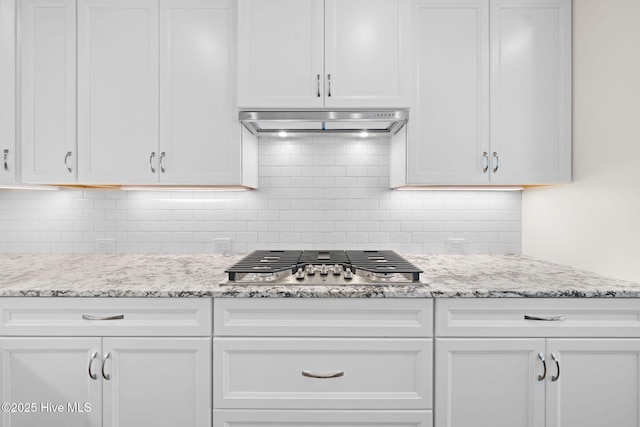 kitchen featuring white cabinets, under cabinet range hood, stainless steel gas cooktop, and decorative backsplash