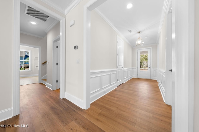 hall with crown molding, stairs, visible vents, a decorative wall, and wood finished floors