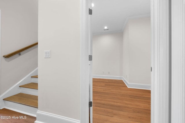 staircase with wood finished floors, baseboards, ornamental molding, and recessed lighting