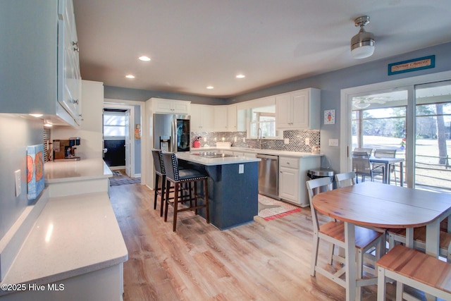 kitchen featuring stainless steel appliances, a breakfast bar area, a kitchen island, and light countertops