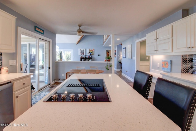 kitchen featuring stainless steel dishwasher, white cabinets, ceiling fan, baseboards, and black electric cooktop