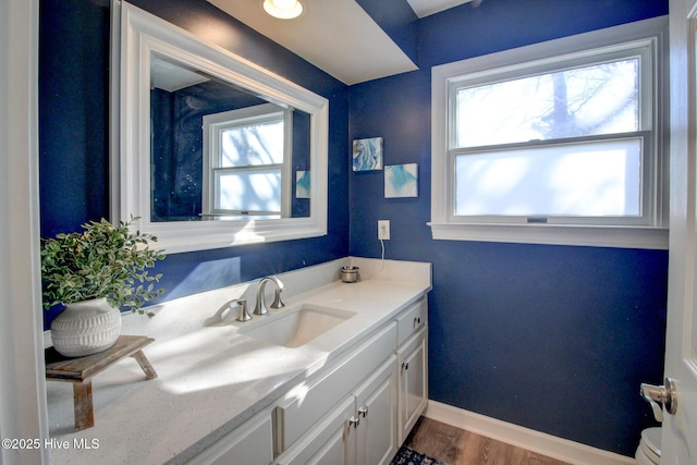 half bathroom with toilet, baseboards, wood finished floors, and vanity