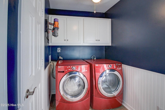 laundry area featuring a wainscoted wall, cabinet space, and independent washer and dryer