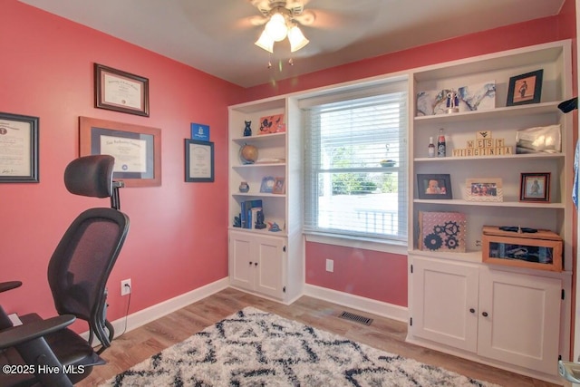 office space with light wood-style floors, visible vents, baseboards, and a ceiling fan