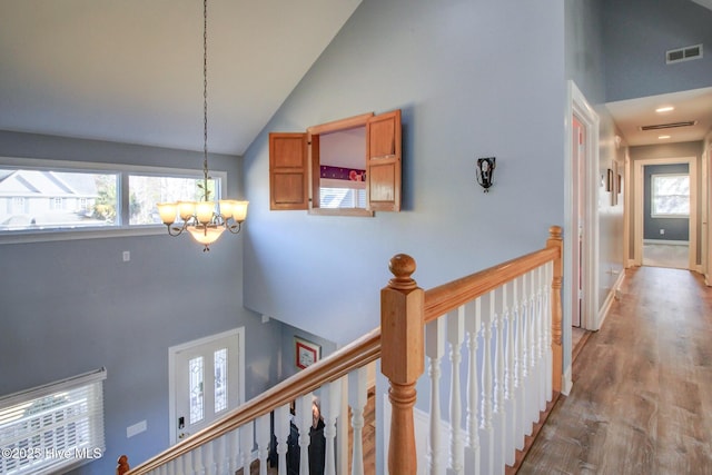 hall featuring high vaulted ceiling, visible vents, wood finished floors, and an upstairs landing