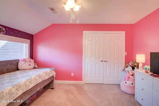 bedroom with baseboards, visible vents, light colored carpet, lofted ceiling, and a closet