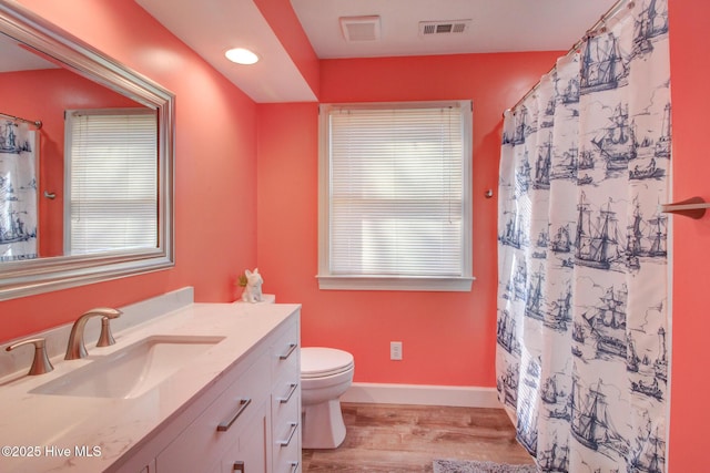 bathroom featuring visible vents, toilet, vanity, wood finished floors, and baseboards